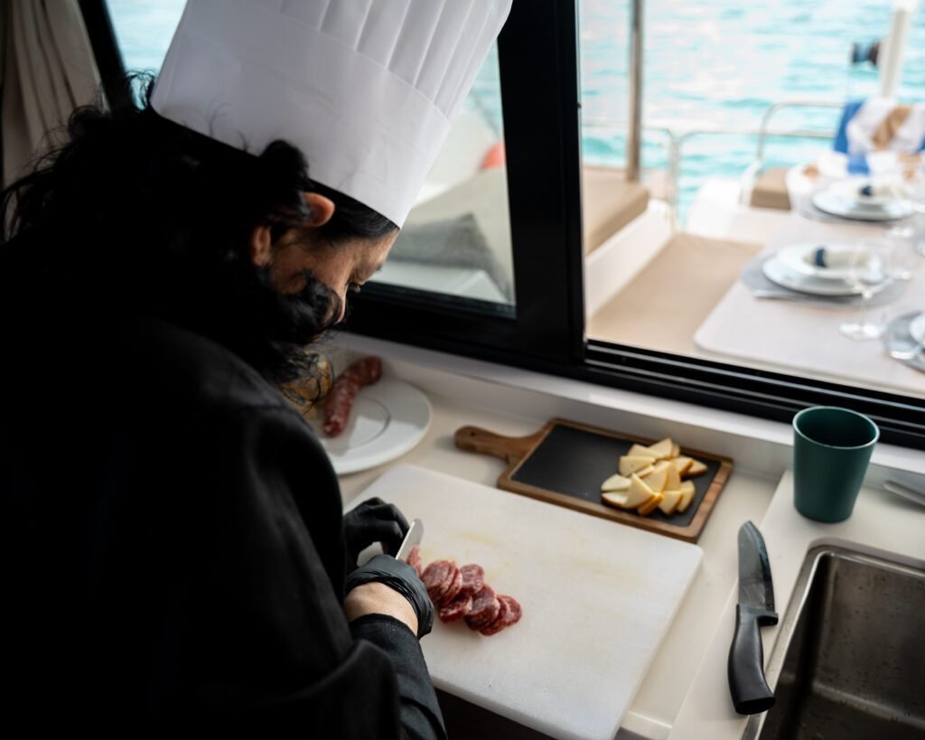 Chef privata al lavoro durante un servizio esclusivo, mentre prepara piatti gourmet in una cucina vista mare